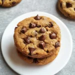 Close-up of stacked homemade chocolate chip protein cookies on a white plate.