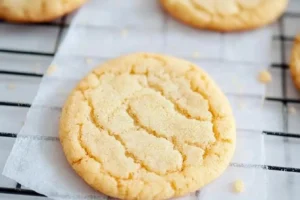 A freshly baked vanilla cookie cooling on parchment paper.