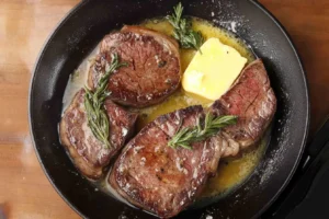 Pan-seared steaks with rosemary and butter in a cast-iron skillet.