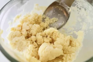 Almond cookie dough being mixed in a glass bowl.