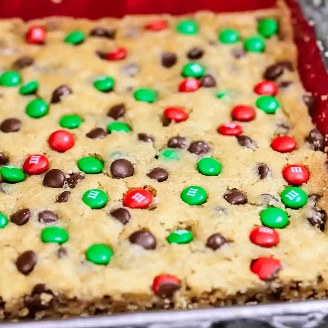 Freshly Baked M&M Cookie Bars Freshly baked M&M cookie bars in a red baking pan, loaded with chocolate chips and festive red and green M&M’s