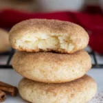 A stack of cinnamon cream cheese cookies with a bite taken out of the top cookie, showing a soft interior.